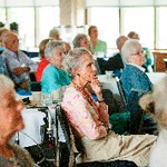 A woman holds her chin contemplatively while sitting next to other people listening